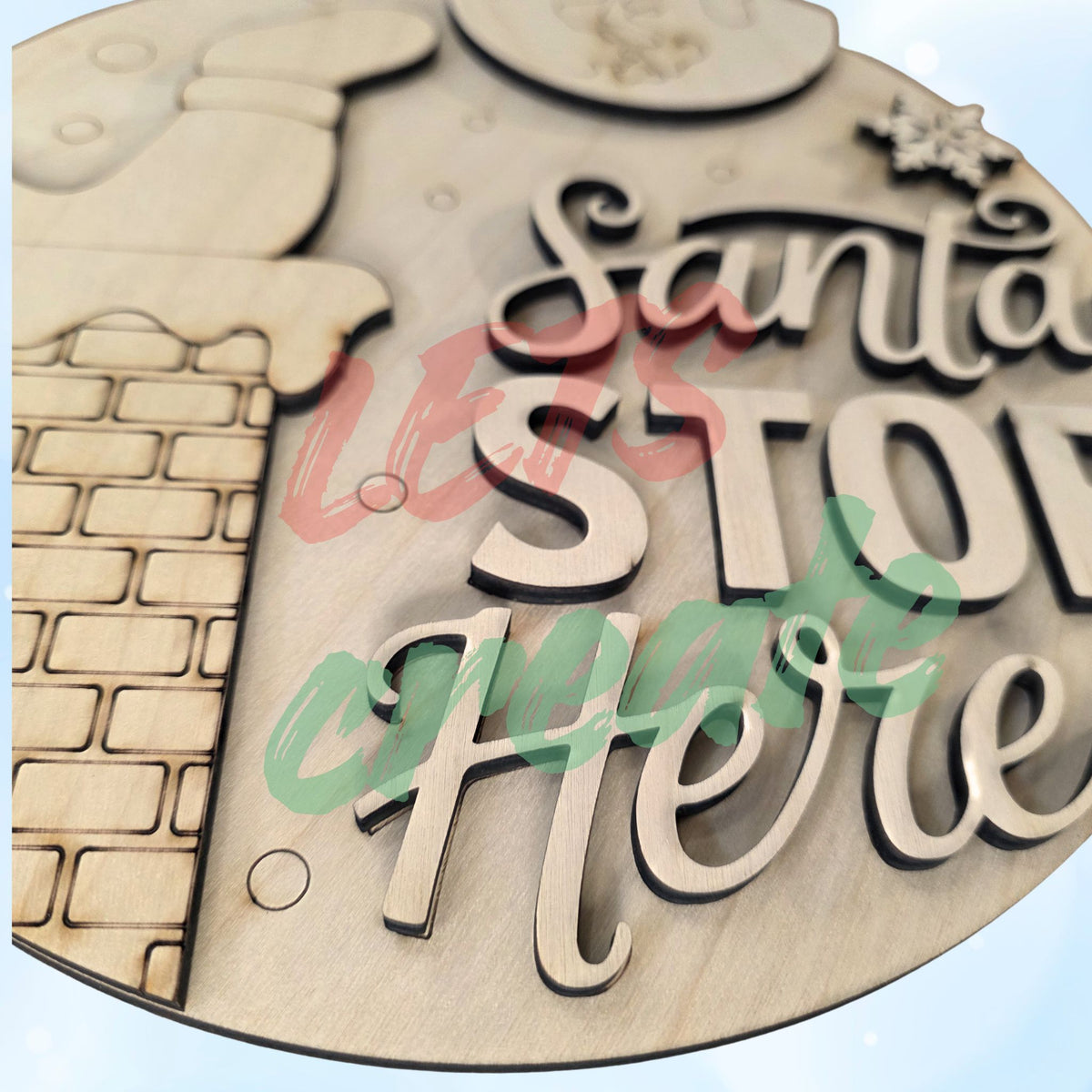 A layered wooden Christmas sign featuring Santa's legs sticking out of a chimney against a background with a snowflake and the moon, displaying the script words "Santa Stop Here" on a white wood plank background.